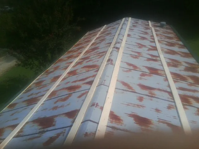 Rusted metal roof panels with new wood purlins before replacement in Marathon