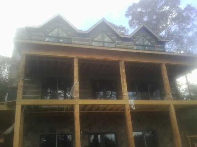 Dormers and porch framing on a large log home under construction — Roof Coating work by our crew in Marathon