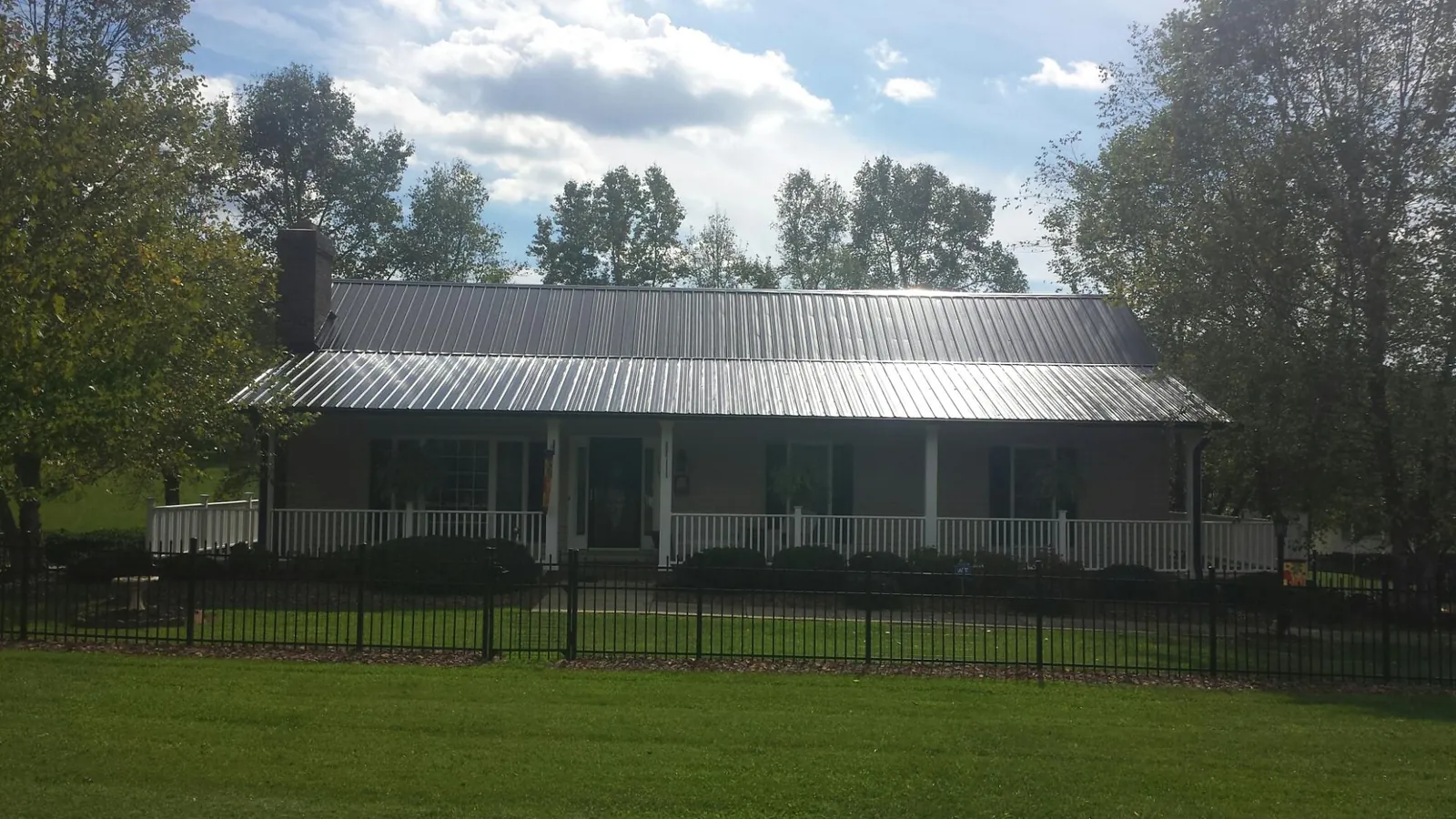 Gray metal roof on a brick ranch with a full width front porch — Gutter Guard Installation work by our crew in Marathon
