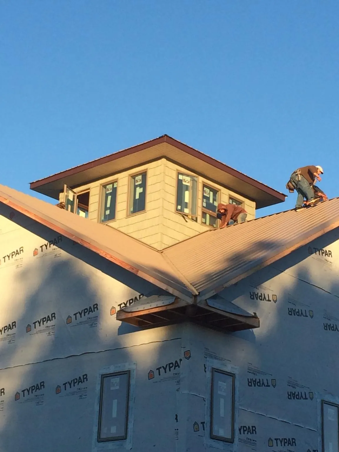Roofers working around a rooftop cupola on a new metal roof at sunset — Roof Waterproofing in Marathon by Roofing Brothers